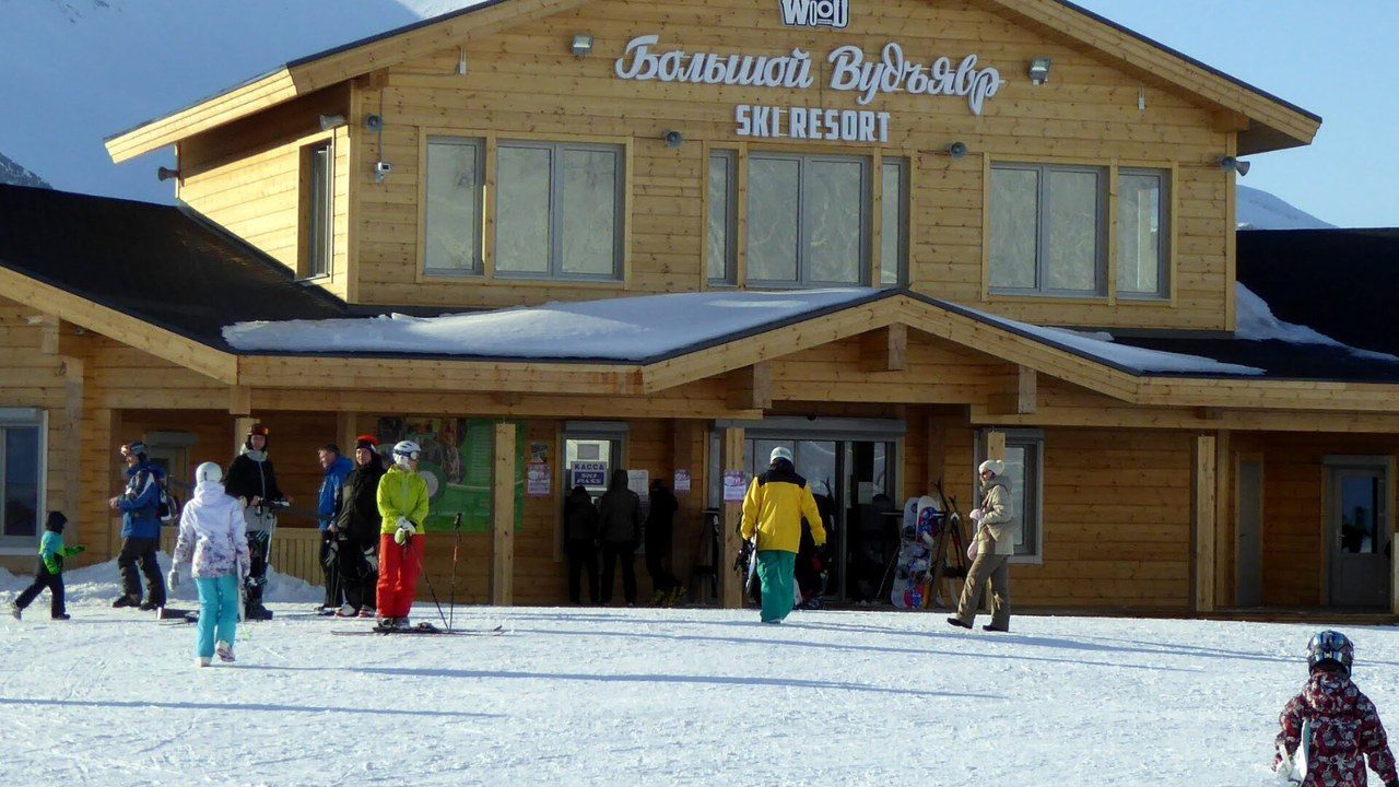 Деревянная база «Большого Вудъявра» и лыжники на снегу перед ней
